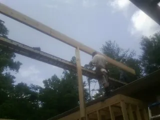Carpenter setting a ridge beam over a new addition frame — Ice Dam Removal by Roofing Brothers in Lamont