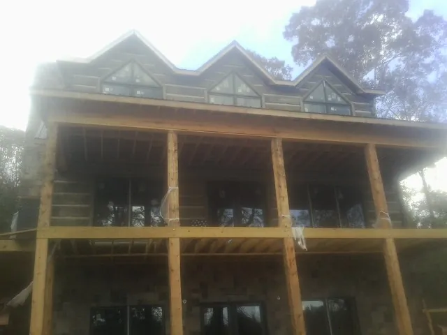 Dormers and porch framing on a large log home under construction — Roof Coating work by our crew in Lamont