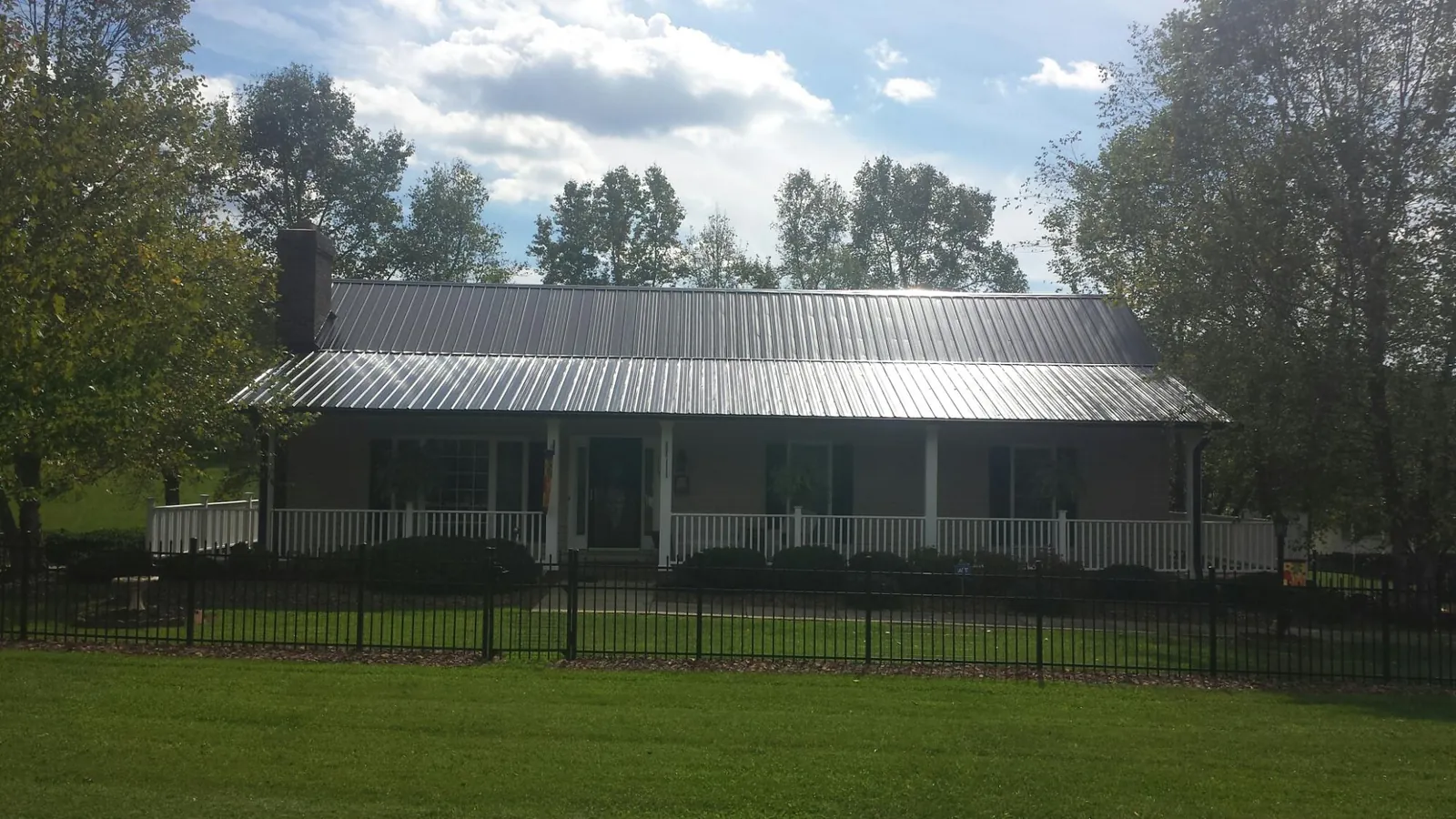 Gray metal roof on a brick ranch with a full width front porch — Gutter Guard Installation work by our crew in Lamont